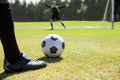 Low section of soccer player with ball against goalkeeper