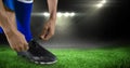 Low section of soccer player typing shoelace