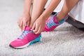 Low section of sportswoman tying shoelaces on sneakers in bedroom