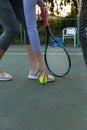 Low section of woman holding tennis racket picking up ball on outdoor tennis court, with copy space Royalty Free Stock Photo