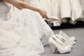 Low section of woman sitting with variety of footwear in bridal boutique