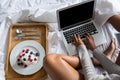 Low section of woman using laptop by breakfast on bed Royalty Free Stock Photo