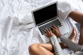 Low section of woman using laptop while relaxing on bed Royalty Free Stock Photo
