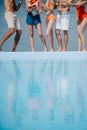 low section young young people standing near pool and drinking champagne