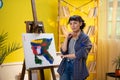 A low shot of an artist with short hair painting something very chic and modern with her paintbrush onto a canvas in Royalty Free Stock Photo