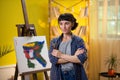 A low shot of an artist with short hair painting something very chic and modern with her paintbrush onto a canvas in Royalty Free Stock Photo