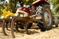 Low shot of rusted old plough attached to the back of a red tractor for planting crops