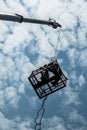 Low silhouettes of workers in steel baskets with sky clouds