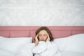 Low-spirited young woman with headache lying in bed