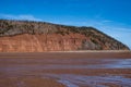 Sand bar off at low tide showing beautiful red sand cliff face with trees and blue sky Royalty Free Stock Photo