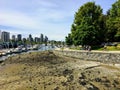 Low tide in Coal Harbour as people enjoy a beautiful day walking and biking along the sea wall in Stanley Park, in Vancouver