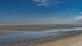 Low tide. Puddles and rivulets of water formed on the exposed wavy sandy seabed.