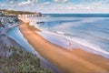 Low tide at Stone Bay, Broadstairs, Kent as summer turns to autumn, a lone surfer walks on the beach and a family on Royalty Free Stock Photo