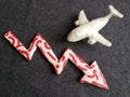 white plasticine airplane and arrow down in red with white on dark gray background