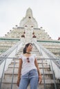 Lowangle view Portrait beautiful Asian woman in a white T-shirt looking away at the Wat Arun temple while traveling in Thailand Royalty Free Stock Photo