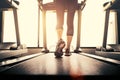 Lower body at legs part of Fitness girl running on running machine or treadmill in fitness gym with sun ray. Warm tone. Healthy Royalty Free Stock Photo