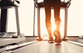 Lower body at legs part of Fitness girl running on running machine or treadmill in fitness gym with sun ray. Warm tone. Healthy Royalty Free Stock Photo