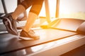 Lower body at legs part of Fitness girl running on running machine or treadmill in fitness gym with sun ray. Warm tone. Healthy Royalty Free Stock Photo