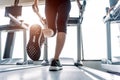 Lower body at legs part of Fitness girl running on running machine or treadmill in fitness gym with sun ray. Warm tone. Healthy Royalty Free Stock Photo