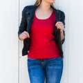 Lower body woman in red t shirt and black leather jacket against white metal door in city t shirt mock up