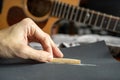 Lower the height of an acoustic guitar saddle for a better playability by sanding down a bone saddle with sandpaper Royalty Free Stock Photo