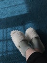 the lower part of the legs in white slippers on a blue carpet on the floor Royalty Free Stock Photo