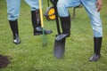 Lower section of couple holding shovel and rake