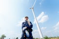 Lower view professional technician worker man stand in front of wind turbine or windmill with blue sky Royalty Free Stock Photo