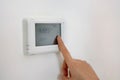 Lowering the temperature for energy saving. Human hand adjusting digital central heating thermostat at home Royalty Free Stock Photo