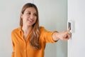 Lowering the temperature for energy saving. Young woman adjusting digital central heating thermostat at home. Focus on the hand Royalty Free Stock Photo