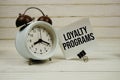 Loyalty Programs text message on sticky note with alarm clcok on wooden background Royalty Free Stock Photo