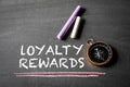 Loyalty Rewards. Text, compass and colored pieces of chalk on blackboard background Royalty Free Stock Photo