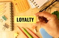 LOYALTY wood word on compressed board with human& x27;s finger at Y letter