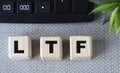 LTF - acronym on wooden cubes on a gray background with a calculator