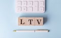 LTV on wooden cubes with pen and calculator, financial concept Royalty Free Stock Photo