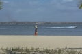 Luanda/Angola - 11 11 2018: View at the beach on Mussulo Island, with a woman walking, water with a boat jet, Luanda city and the