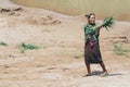 Luang Prabang, Laos - April 2019: Laotian woman carries cane leaves on the riverfront