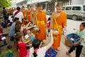 Monks collect alms and offerings during daily early morning procession in Luang Prabang, Laos.