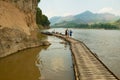 Tourists stand at the bamboo pier next to the Tham Ting cave with over 4000 Buddha figures in Luang Prabang, Laos