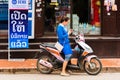 LUANG PRABANG, LAOS - JANUARY 11, 2017: Woman on a moped on a city street. Copy space for text.