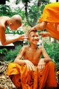 young buddhist monks shaving each others head in preparation for a holy festival event