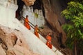 LUANG PRABANG, LAOS - MARCH 22, 2018: Monk in hundreds of Buddha statues inside Pak Ou Caves, Luang Prabang in Laos
