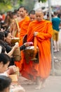 Luang Prabang, Laos - May 2019: Laotian people making offerings to Buddhist monks during alms giving ceremony