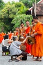 Luang Prabang, Laos - May 2019: Laotian people making offerings to Buddhist monks during alms giving ceremony