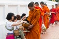 Luang Prabang, Laos - May 2019: Laotian woman making offerings to Buddhist monks during alms giving ceremony