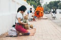 Luang Prabang, Laos - May 2019: Laotian woman making offerings to Buddhist monks during alms giving ceremony