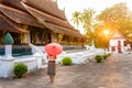 Luang Prabang Laos, woman in Laos dress with umbrella standing at Xienthong temple in sunset light Royalty Free Stock Photo