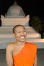 Luang Prabang, Laos - 2019-11-18: Young buddhist monk smiling in front of the That Pathoum stupa at the Wat Wisunarat temple