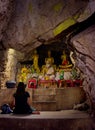 Luang Prabang, Laos - 2019-11-18: Young woman meditating in a buddhist shrine inside a cave at Mt. Phou Si.