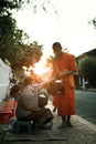 luangprabang lao-july22,2023 : buddhist monk receiving sticky rice from villager in luangprabang town street,luang prabang is one